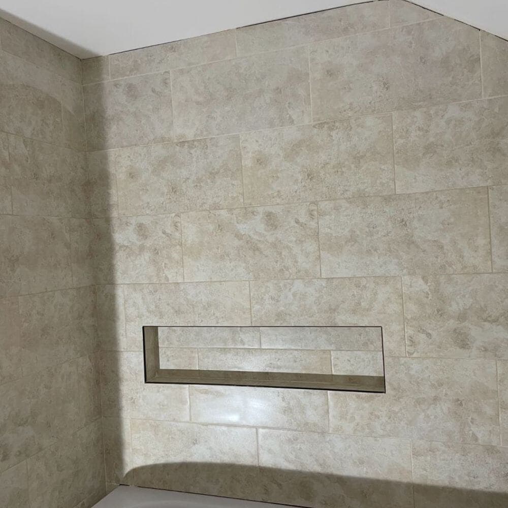 Stone-effect wall tiling with a recessed shower niche, completed by JM Plumbing Services