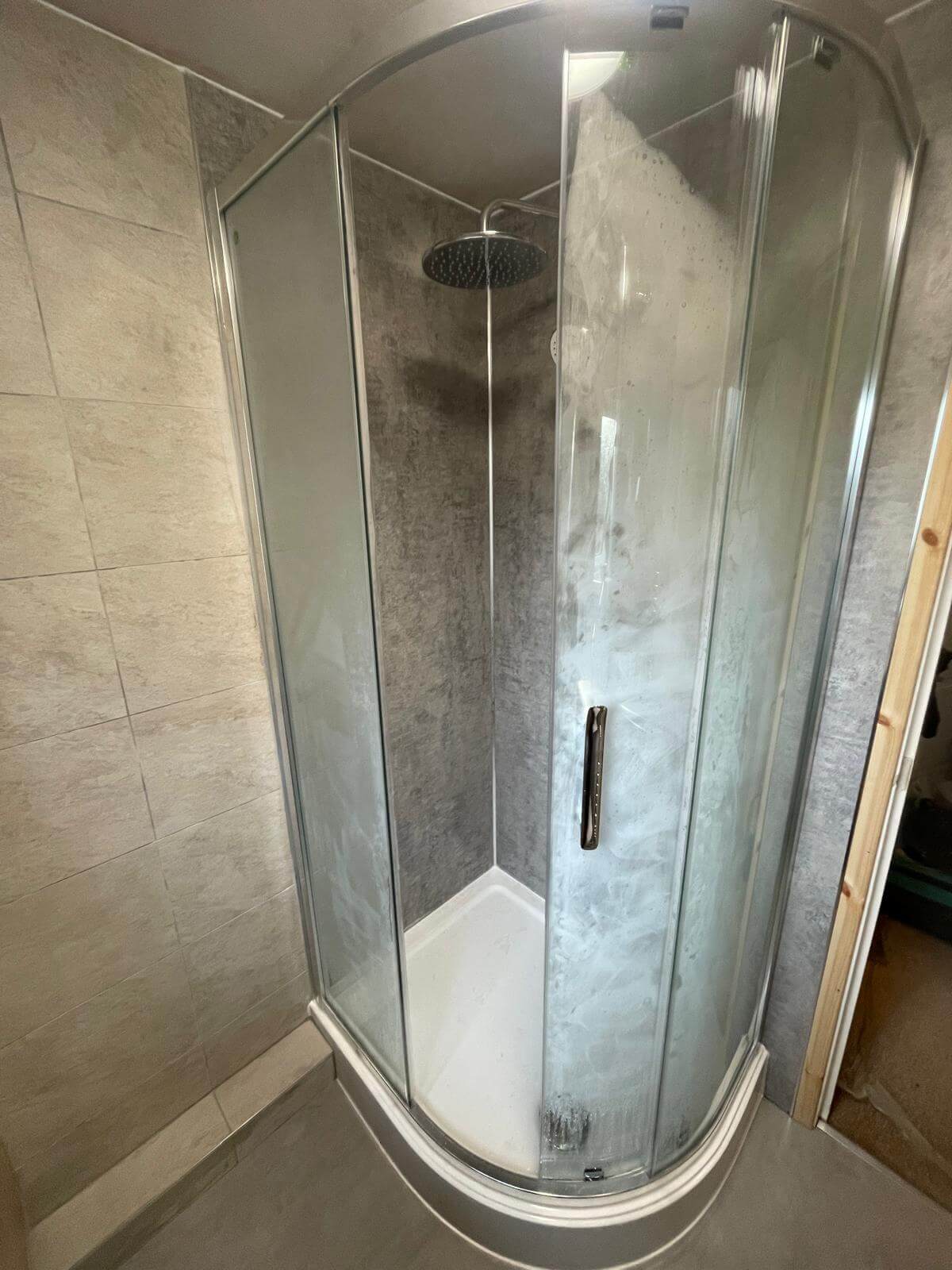 Quadrant glass shower enclosure with stone-effect panelling, fitted in Barry by JM Plumbing Services