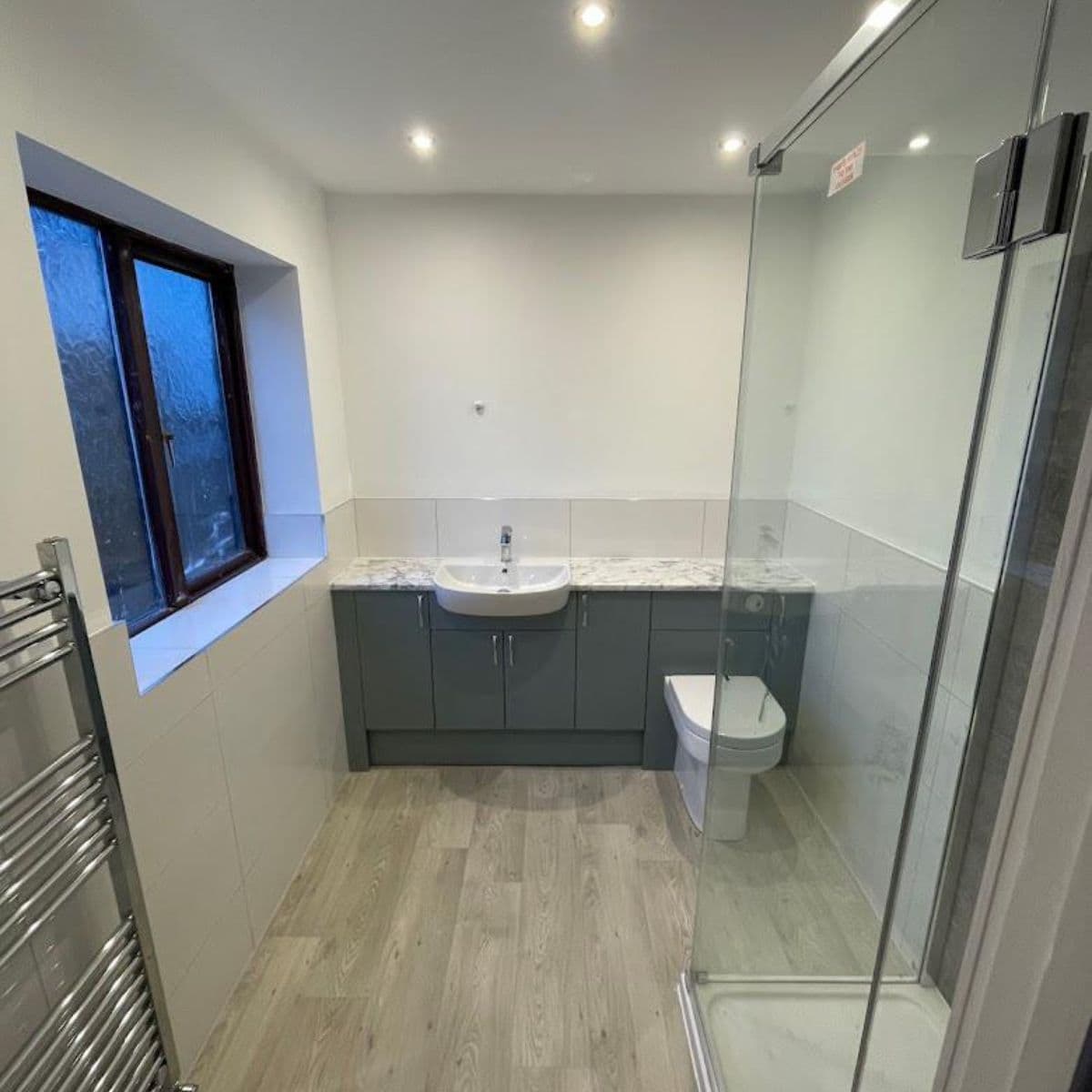 Contemporary bathroom renovation in Cardiff with a glass shower enclosure and marble-effect vanity, completed by JM Plumbing Services